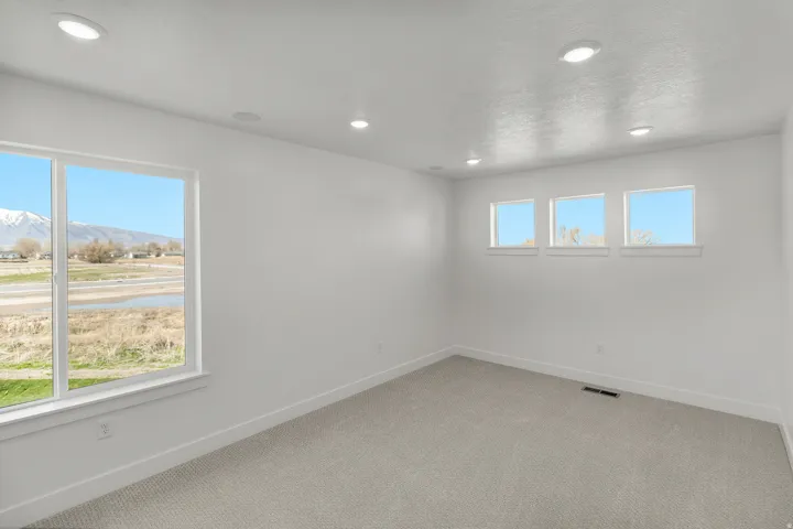 Spacious room with light gray carpeting, recessed ceiling lighting, and crisp white walls