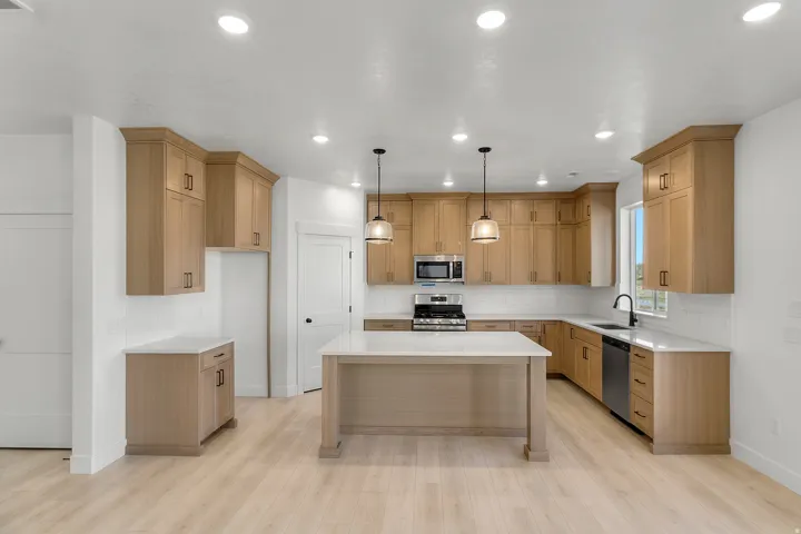Modern kitchen featuring wood-finish cabinetry, white subway tile backsplash, and light-toned wood-finish flooring