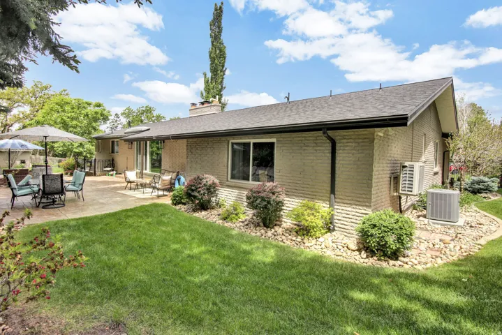 Expansive backyard featuring a large concrete patio, manicured lawn, and mature landscaping