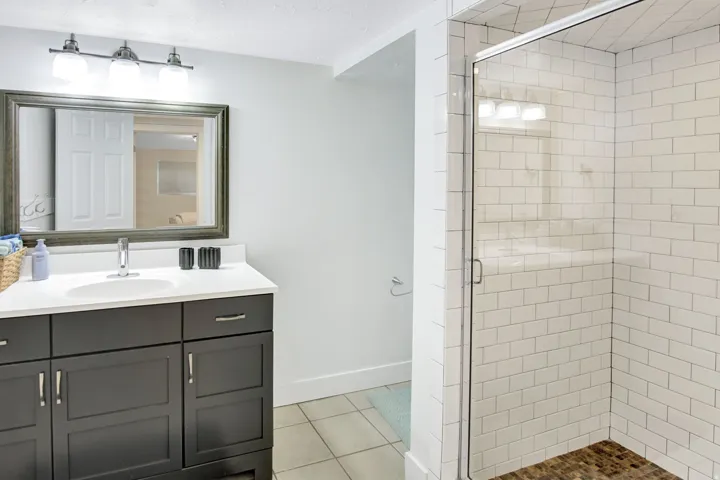 Bathroom featuring a dark wood vanity with a white countertop, an oval undermount sink, and a framed mirror