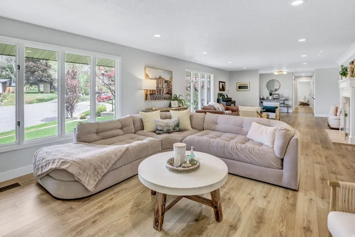 Living area featuring expansive windows, recessed lighting, wood-finish flooring, and a white fireplace with a decorative mantel