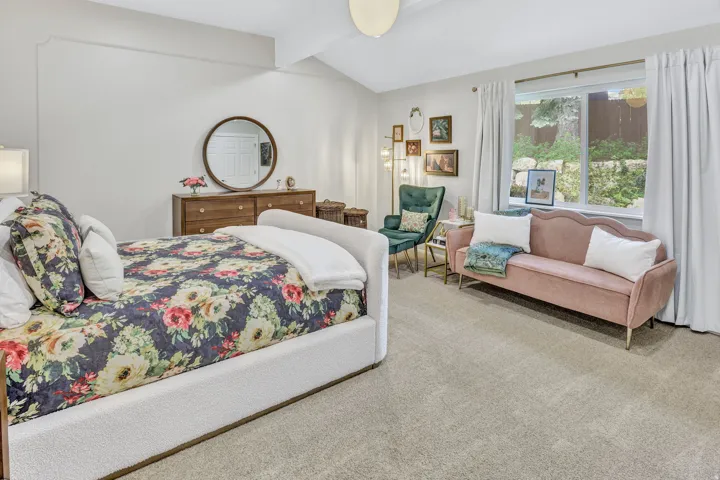 Spacious room featuring vaulted ceilings, ample natural light from a large window, light-toned carpeting, and a built-in wall molding accent