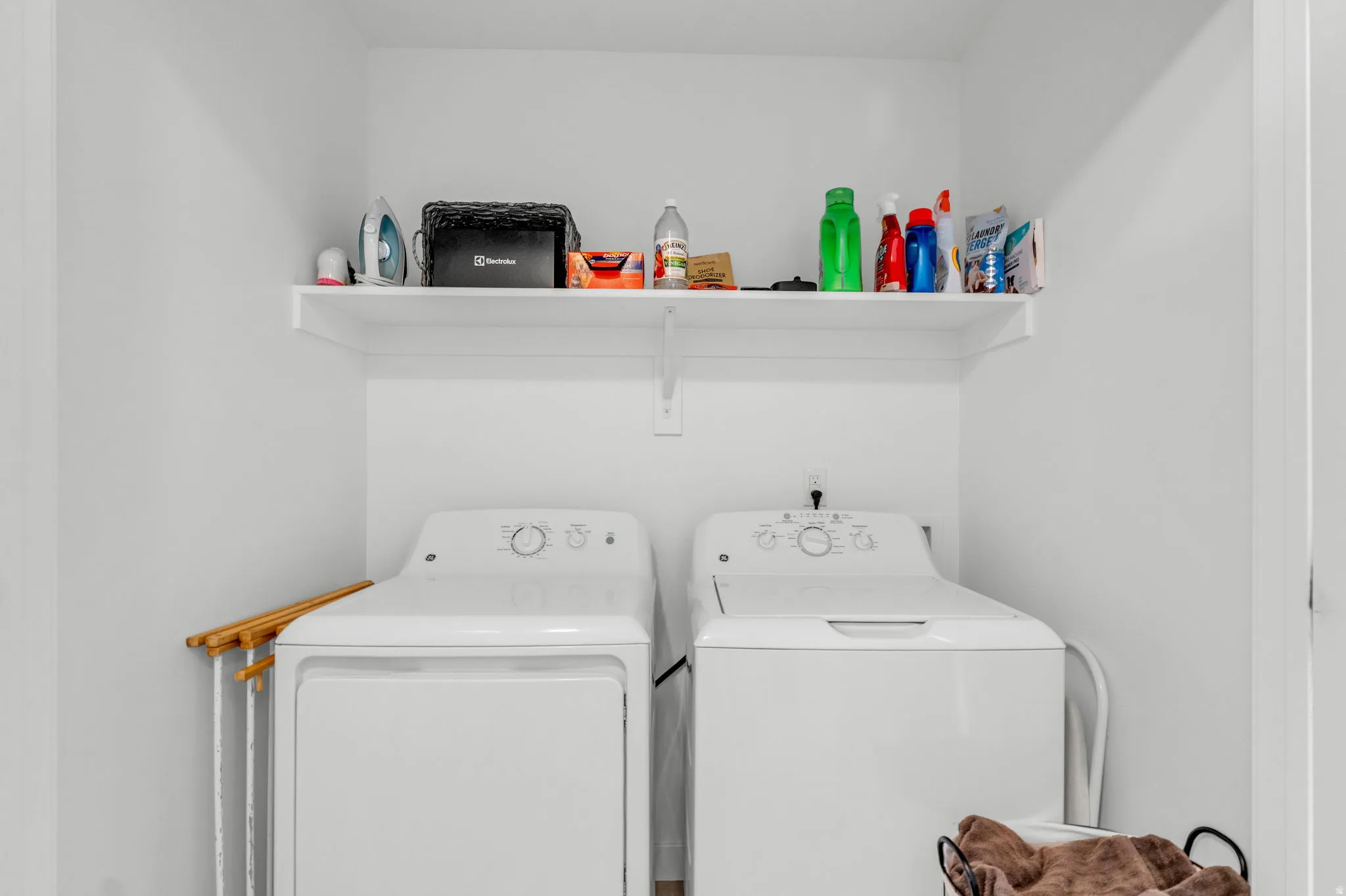 Dedicated laundry area featuring a white floating shelf, white walls, and a visible utility hookup