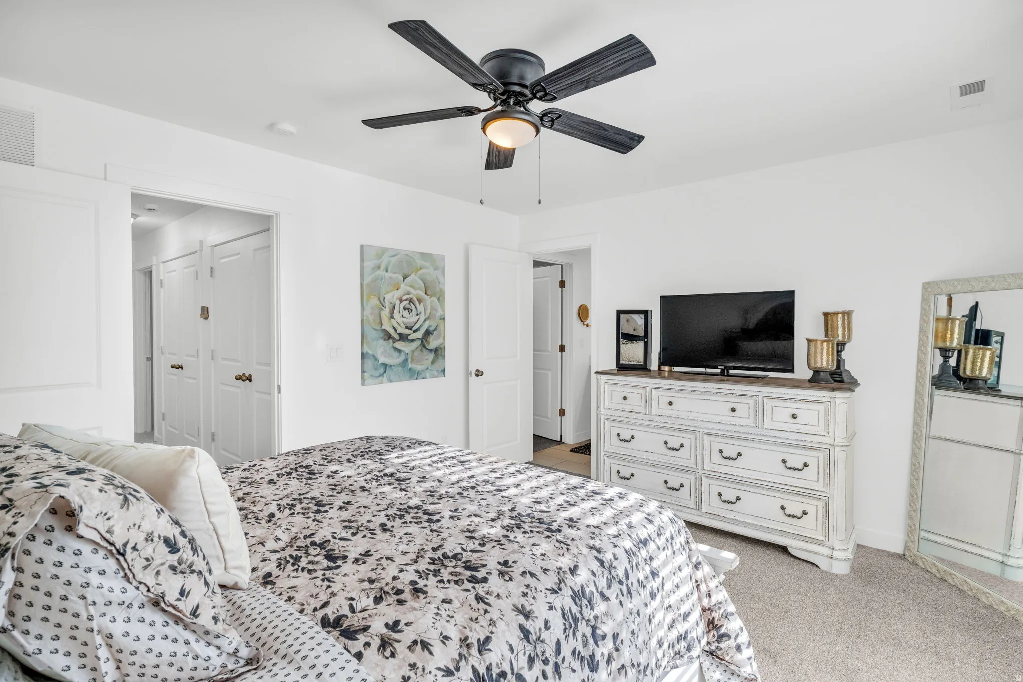 Bright interior room featuring a ceiling fan with light fixture, neutral carpeting, and white walls