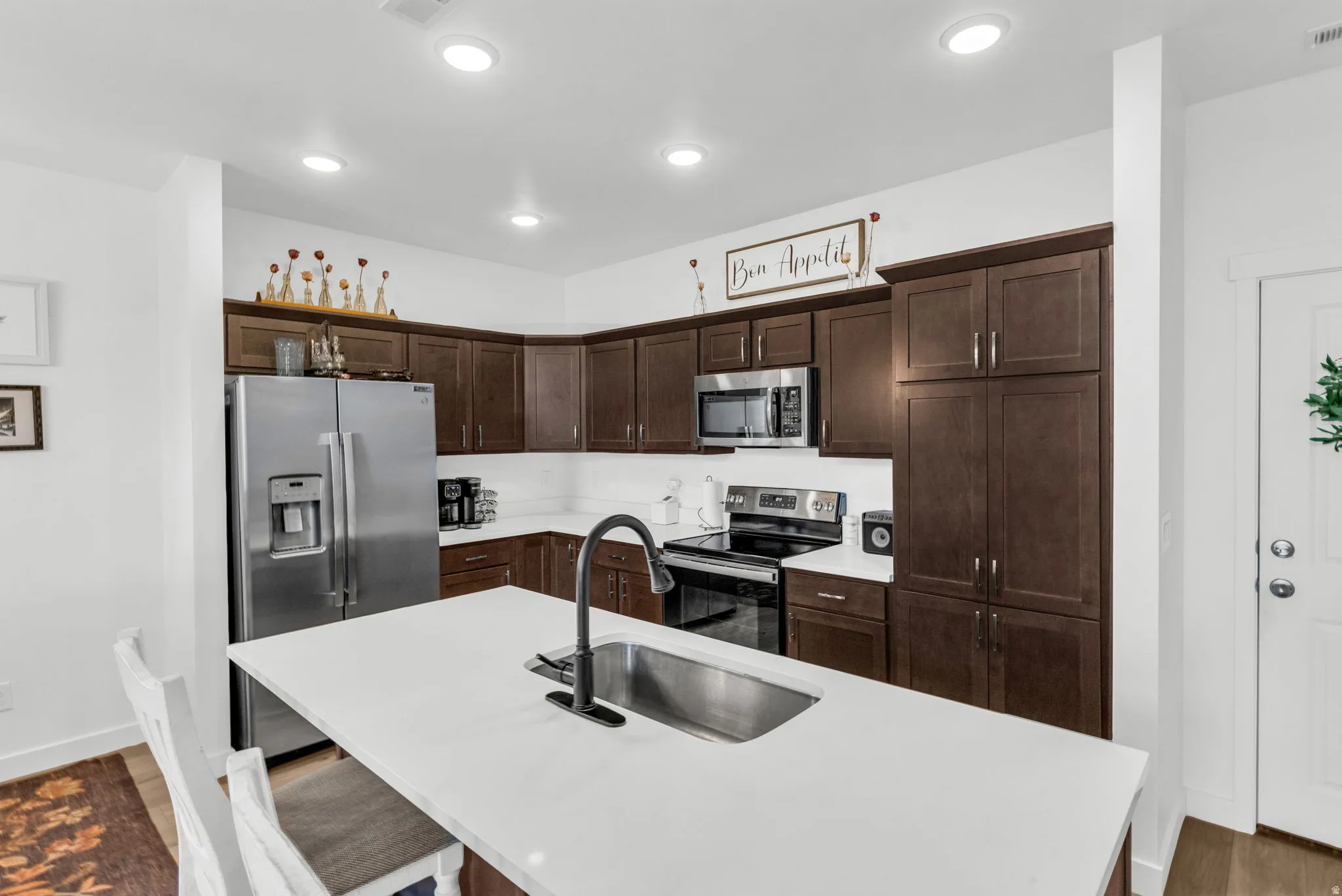 Modern kitchen featuring dark wood cabinetry, white countertops, and stainless steel appliances