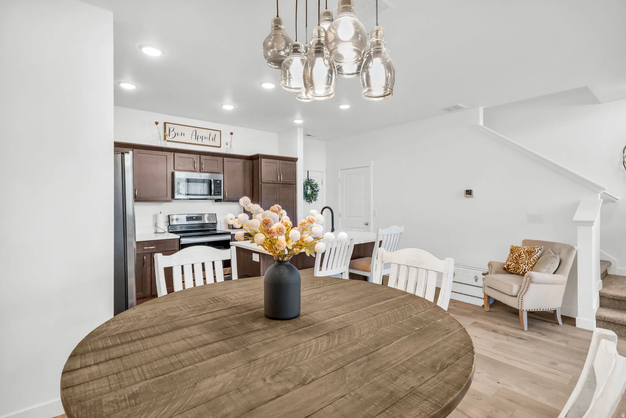 Open-concept dining area featuring a wood-finish round table and a multi-pendant light fixture