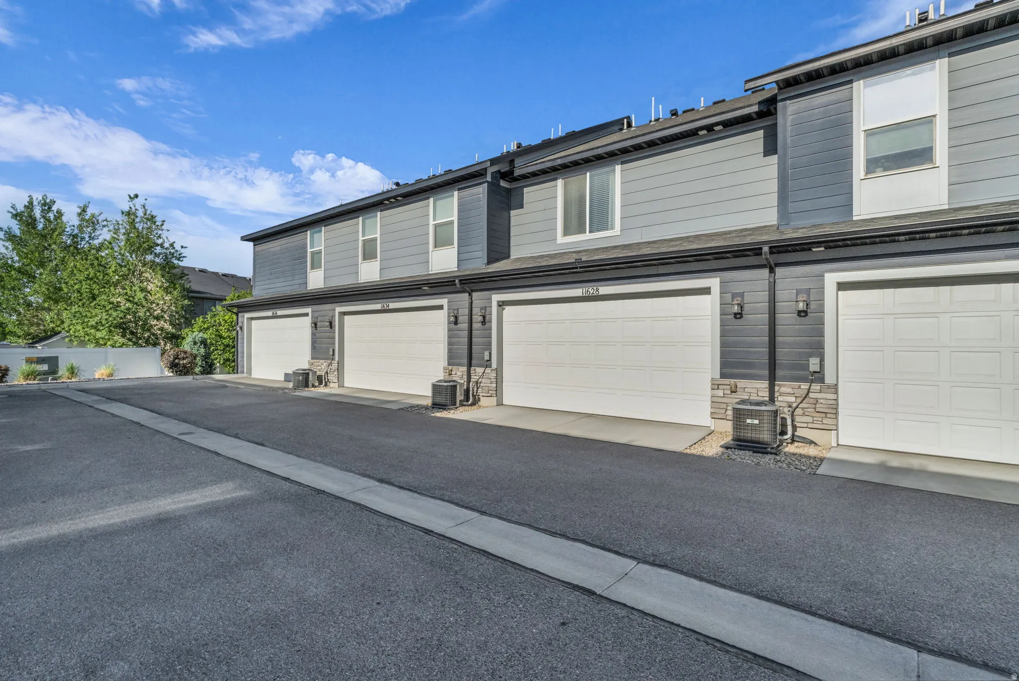 Townhome exterior featuring gray horizontal siding and white garage doors