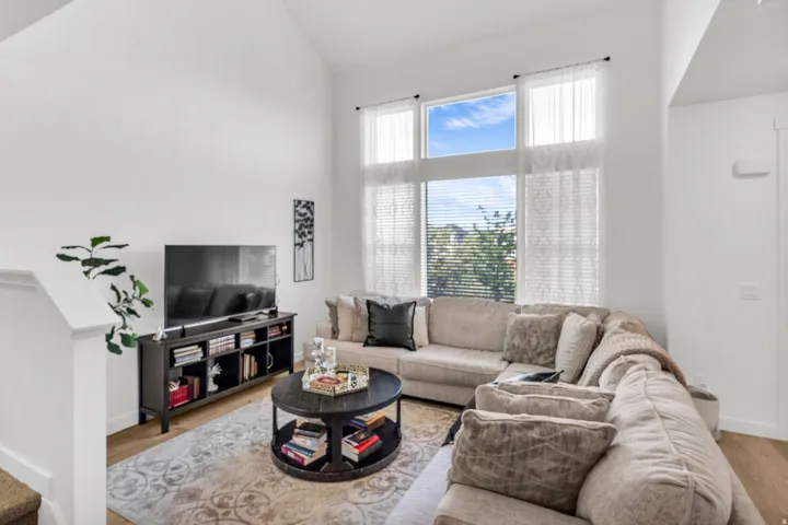 Living area featuring high vaulted ceilings, expansive window wall with transoms, and light wood-finish flooring