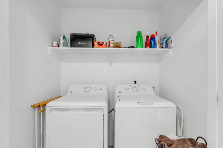 Dedicated laundry area featuring a white floating shelf, white walls, and a visible utility hookup