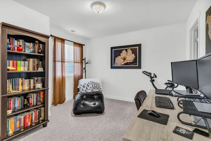 Carpeted room featuring a built-in bookcase, a window with blinds, and white walls