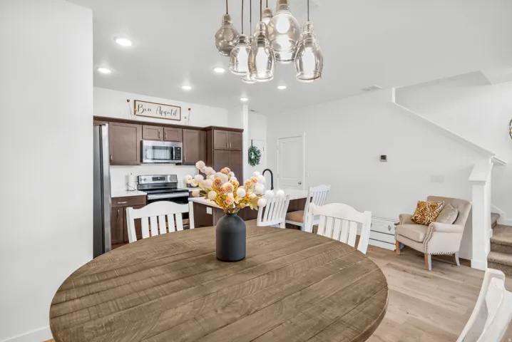 Open-concept dining area featuring a wood-finish round table and a multi-pendant light fixture