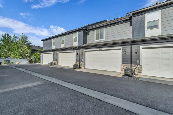 Townhome exterior featuring gray horizontal siding and white garage doors
