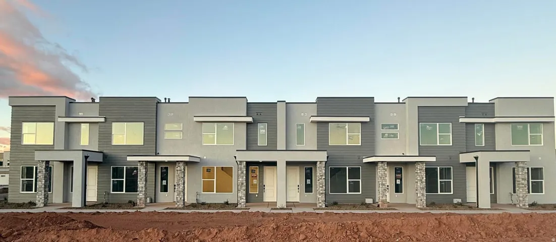 Contemporary townhome exteriors featuring multiple window styles, flat roofs, varied grey siding, stucco finishes, and stone veneer accents
