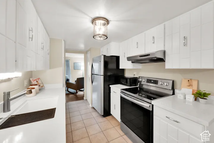 Kitchen featuring white cabinetry with modern hardware, quartz countertops, tile flooring, and stainless-steel appliances