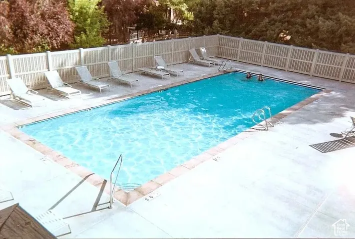 Rectangular swimming pool with a white privacy fence and surrounding concrete decking