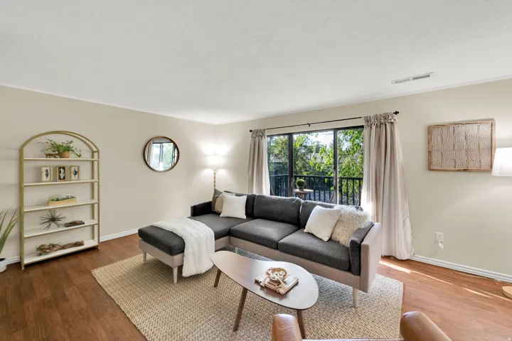 Living area featuring wood-finish flooring, light neutral wall paint, and a sliding glass door opening to an outdoor balcony