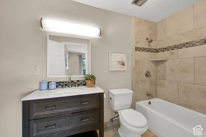 Primary Bathroom featuring a vanity with a white countertop and undermount sink, a tiled tub-shower combination with an accent band, and a built-in shower niche