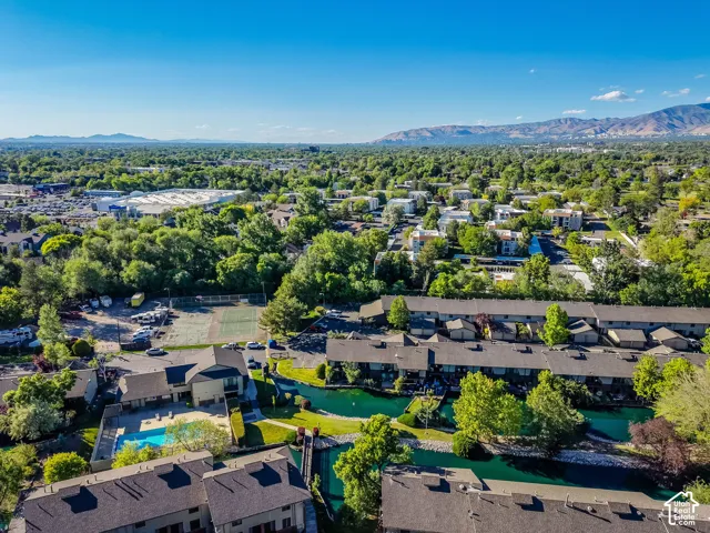 Aerial perspective of property featuring waterfront access, a community swimming pool, and a tennis court