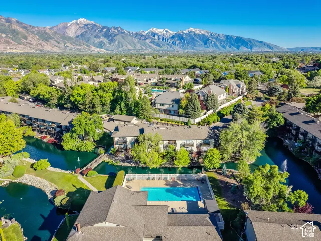 Aerial perspective showcasing a community with a swimming pool, water features, mature landscaping, and mountain backdrop