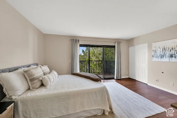 Bedroom featuring wood-finish flooring, light-toned walls, and a large sliding glass door