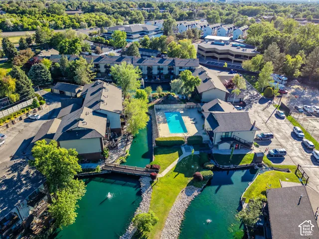 This expansive property features multiple residential buildings alongside a significant water feature with a pedestrian bridge
