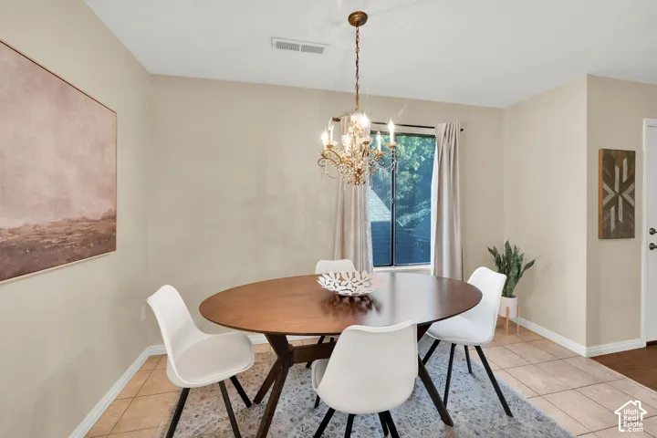 Dining area featuring a brass chandelier, neutral wall tones, and tiled flooring