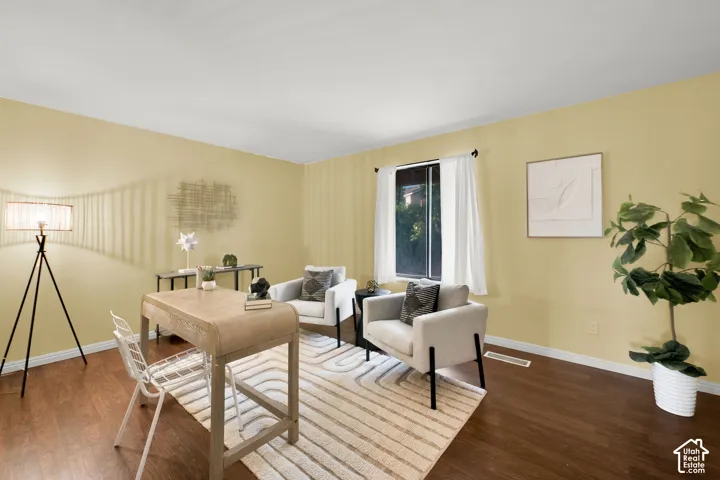 Sunlit interior space featuring wood-finish flooring, a window with white drapery, and neutral-toned wall paint