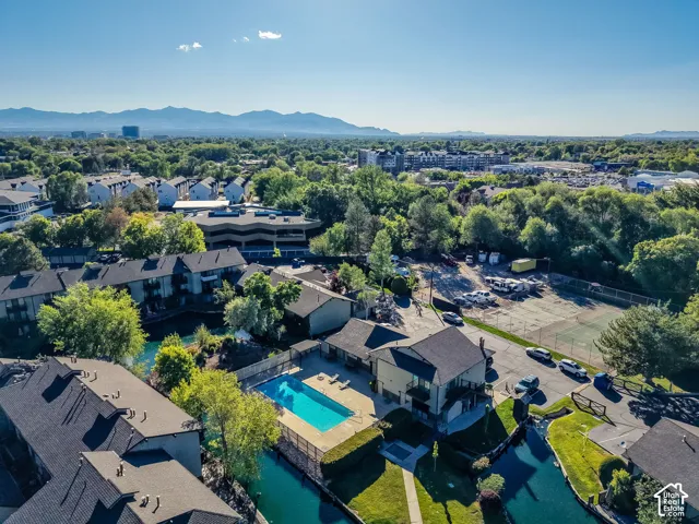Aerial perspective showcasing multiple residential buildings, surrounded by mature trees, with mountain scenery in the distance