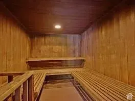 Wood-paneled sauna featuring a built-in bench, upper-level shelving, and recessed lighting