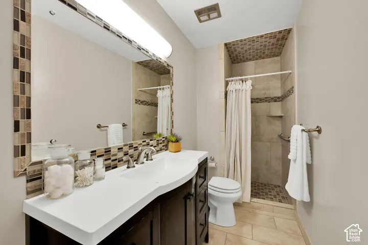 Bathroom featuring a dark wood-finish vanity with a white countertop and undermount sink, brushed nickel faucet, and a large mirror framed with mosaic tile