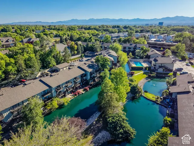 Aerial property perspective featuring multiple residential buildings, a central water feature with a fountain, and an outdoor swimming pool