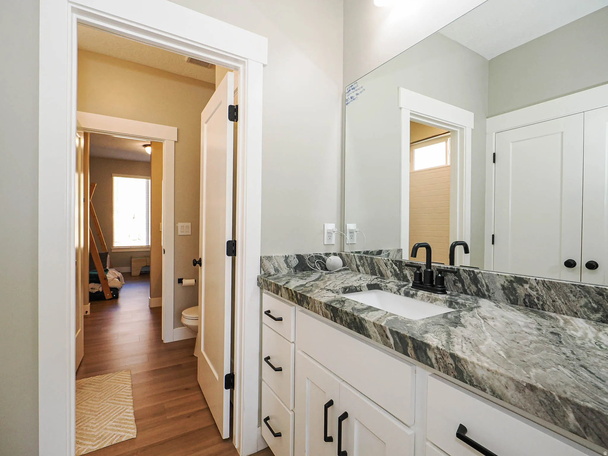 Bathroom vanity with a rectangular undermount sink, a gray and white patterned countertop, and a matte black faucet
