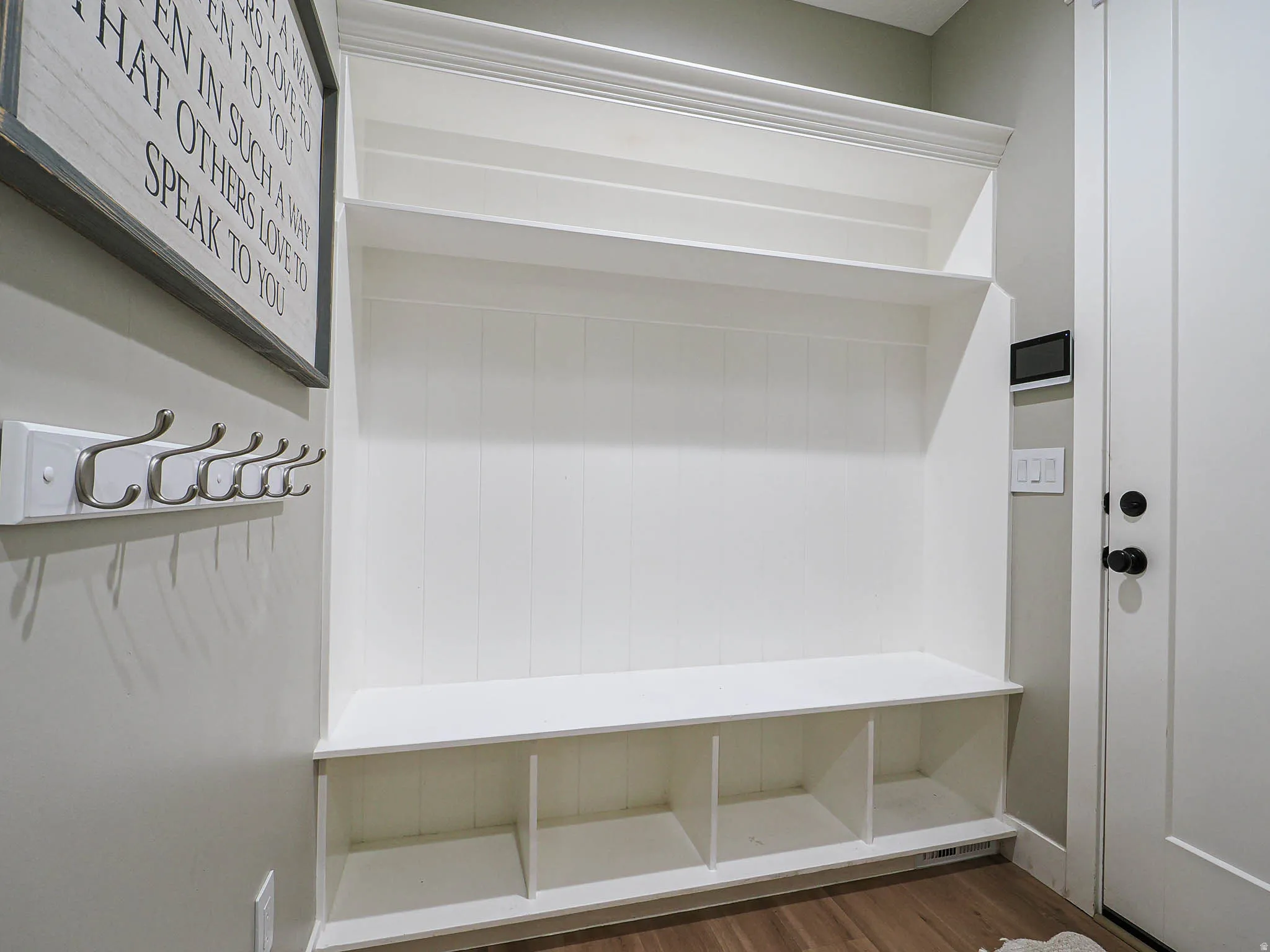 Built-in mudroom bench with cubby storage, upper shelving, and beadboard paneling