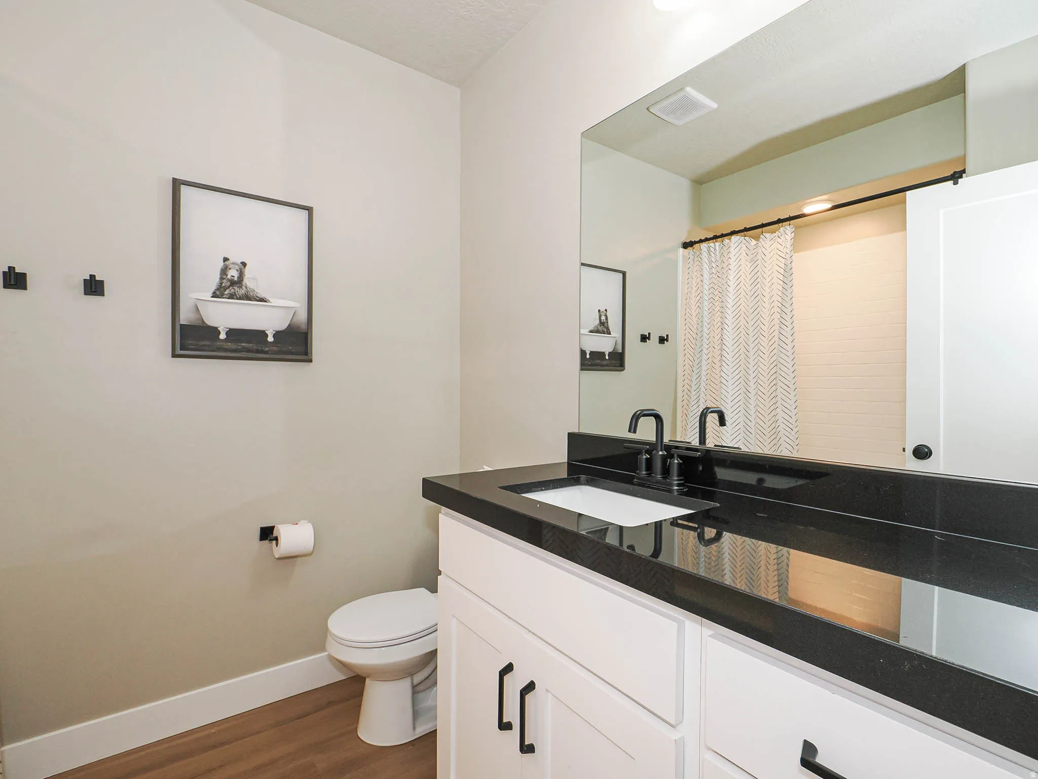 Bathroom featuring a white vanity with black hardware, a polished dark countertop, and a rectangular undermount sink