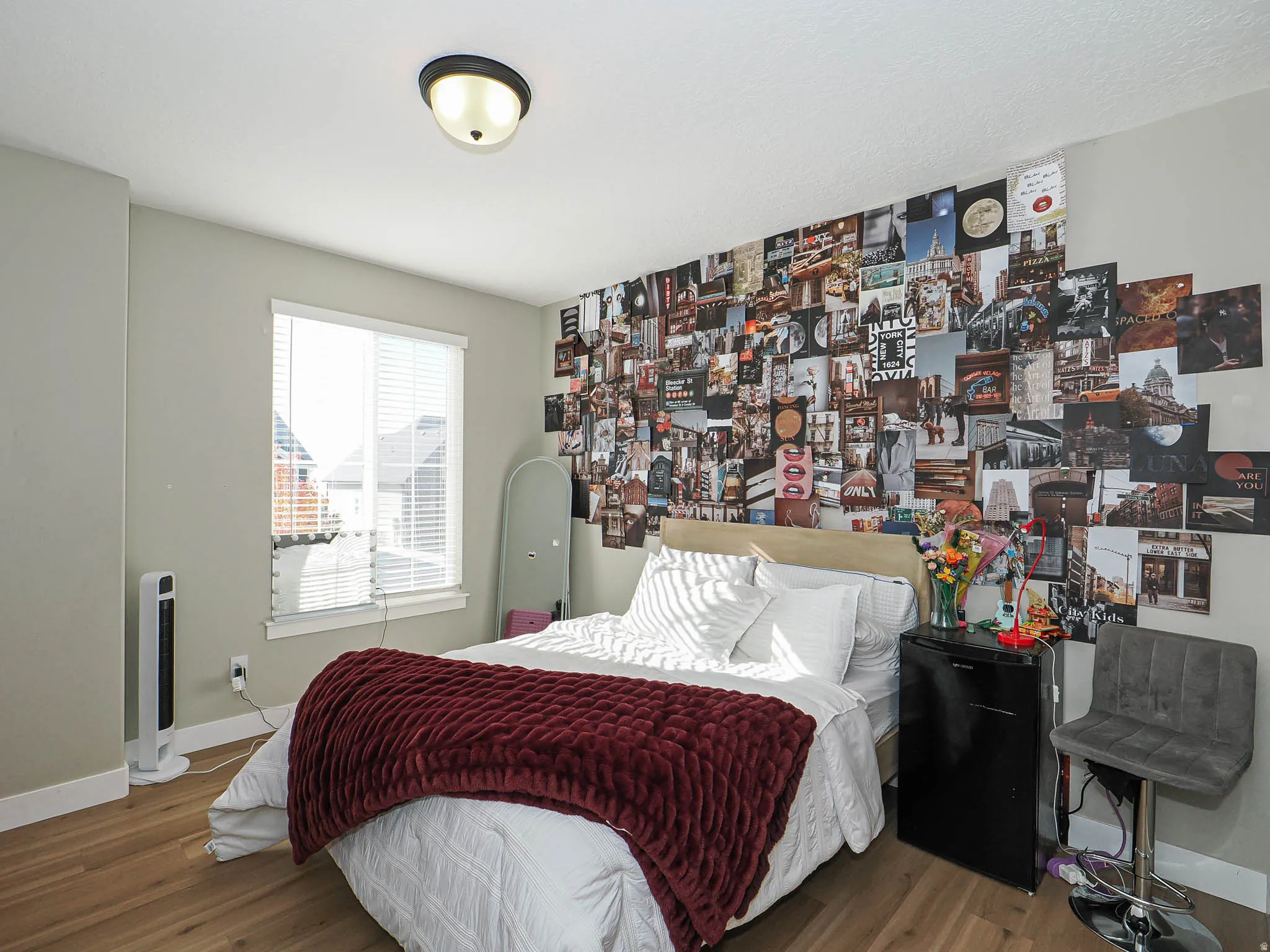 Light-filled room featuring wood-finish flooring, a window with blinds, and a flush-mount ceiling light