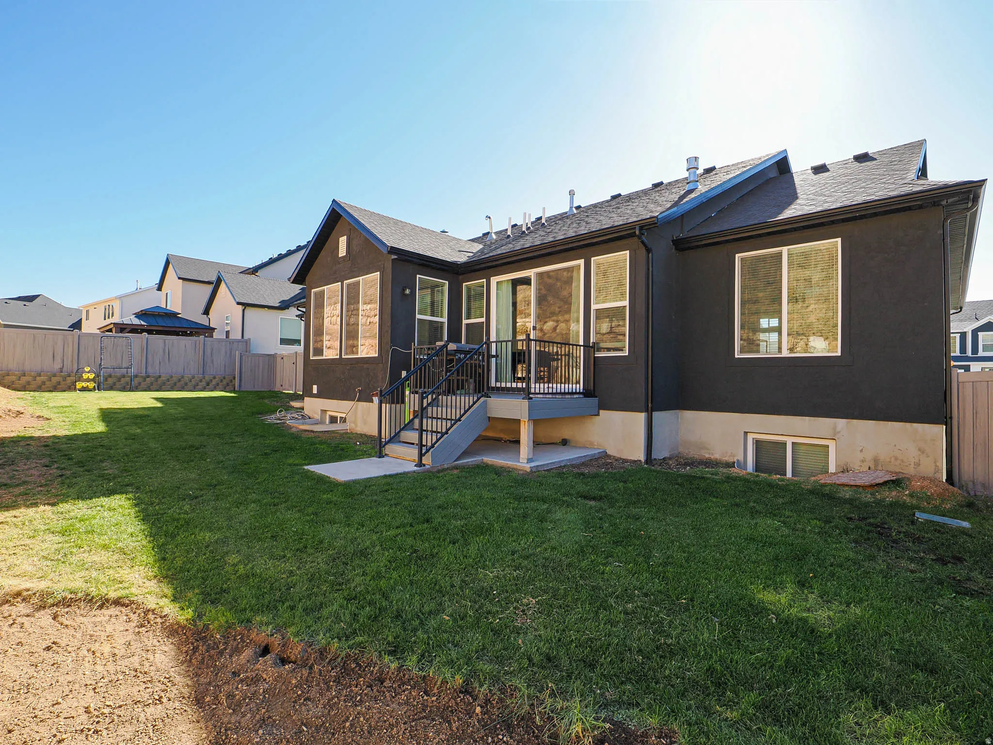 Expansive backyard featuring a new lawn, a concrete patio, and a deck with metal railings