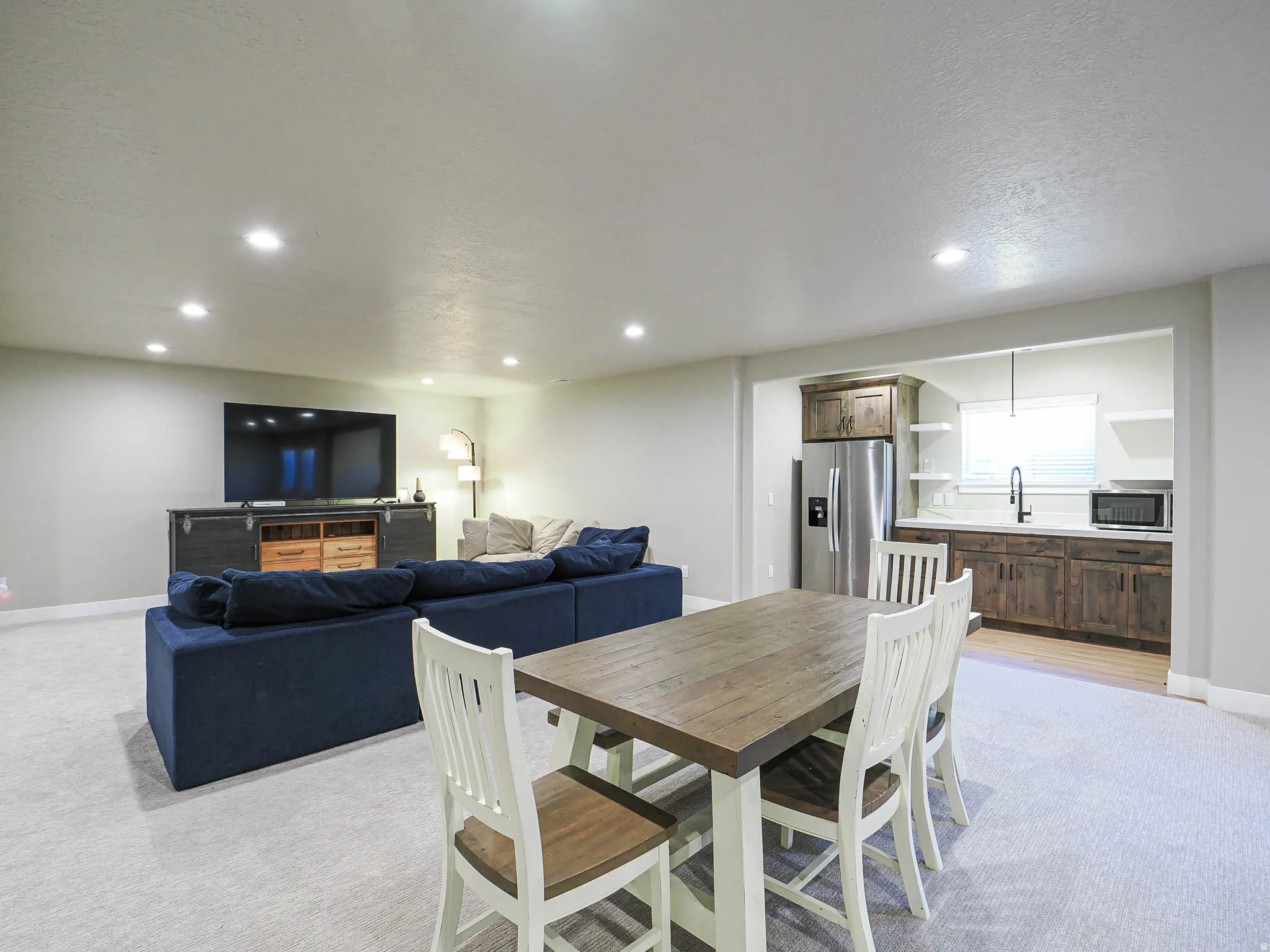 Open-concept living space with recessed lighting, light-toned carpeting, and a dedicated wet bar area
