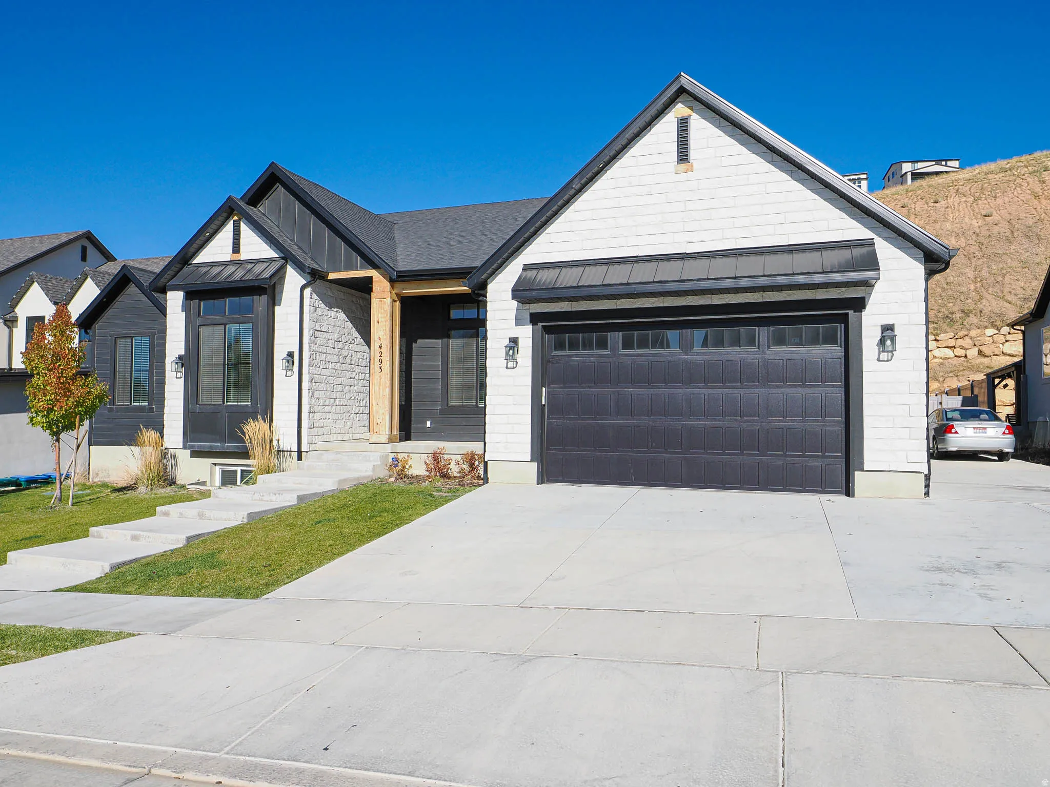 Modern single-story exterior featuring white horizontal siding, dark vertical siding accents, and a stone facade