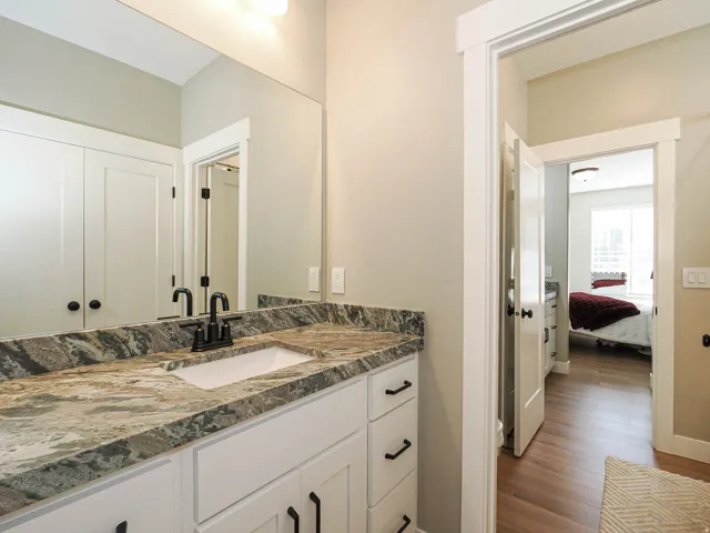 Bathroom vanity featuring a rectangular undermount sink, a patterned countertop, and a matte black faucet