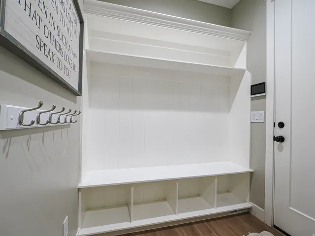 Built-in mudroom bench with cubby storage, upper shelving, and beadboard paneling