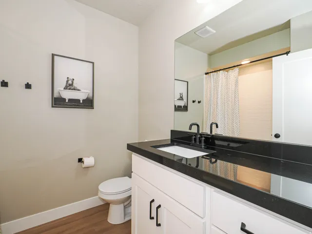 Bathroom featuring a white vanity with black hardware, a polished dark countertop, and a rectangular undermount sink