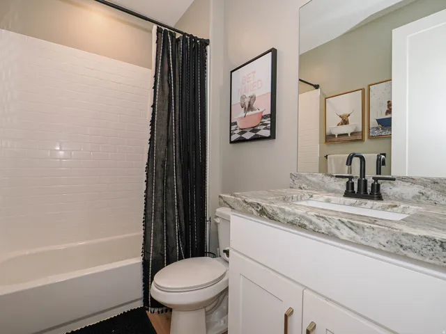 Bathroom featuring white subway tile surround, white bathtub, and a built-in vanity with a stone countertop