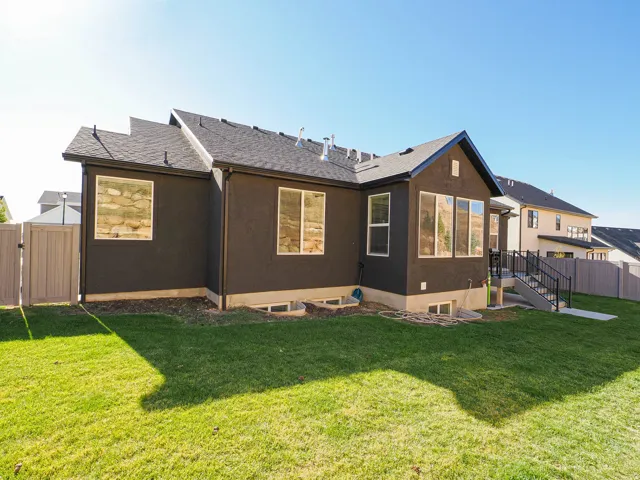 Expansive backyard featuring a manicured lawn, a full privacy fence, and a walk-out basement patio