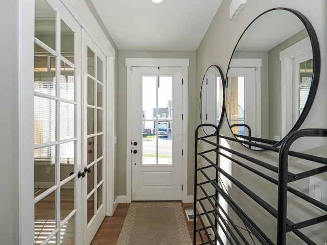 Entryway featuring a white paneled door with glass inserts, wood-finish flooring, and light-toned walls