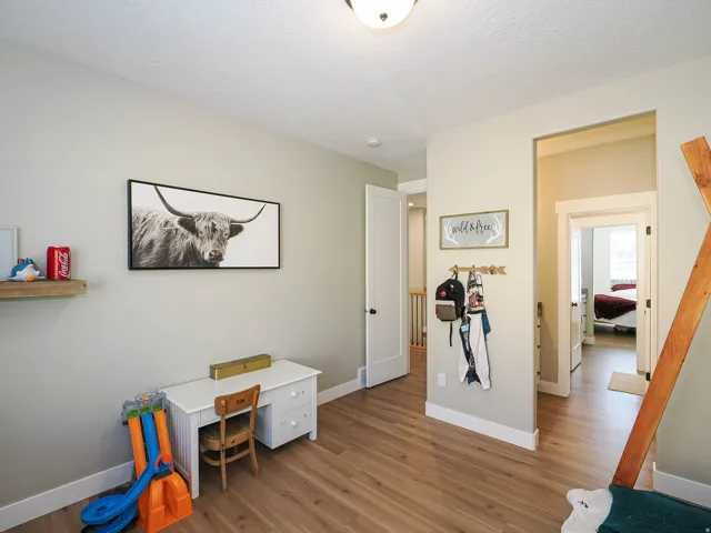Hallway featuring wood-finish flooring, light neutral wall tones, and white trim
