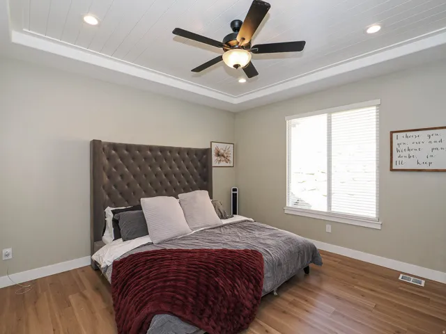 Recessed tray ceiling with shiplap-style finish, light wood-finish flooring, and a ceiling fan with integrated lighting