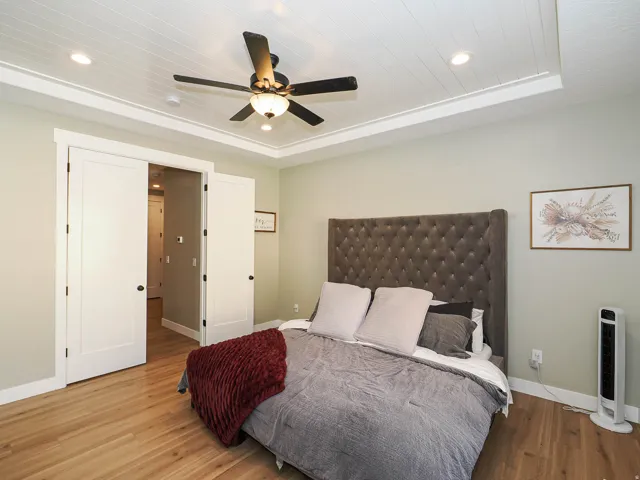 Recessed ceiling with plank-style detailing and a ceiling fan with integrated lighting