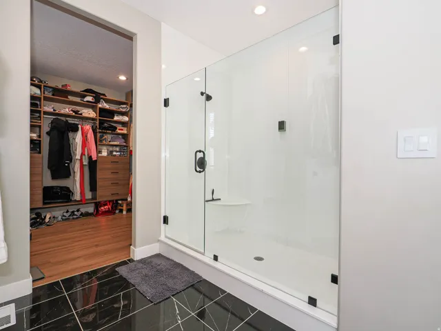 Spacious walk-in shower with clear glass enclosure and matte black fixtures