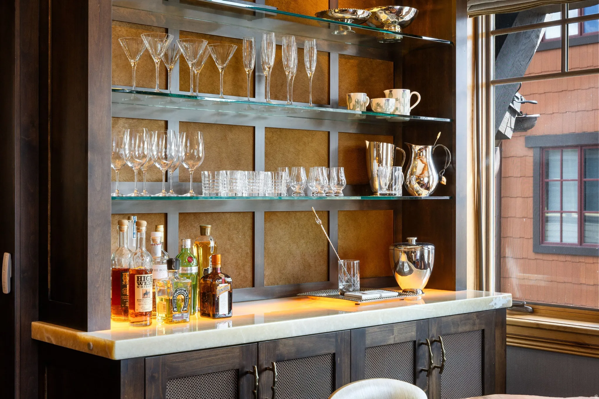 Custom built-in bar featuring dark wood cabinetry with textured inserts and bronze hardware