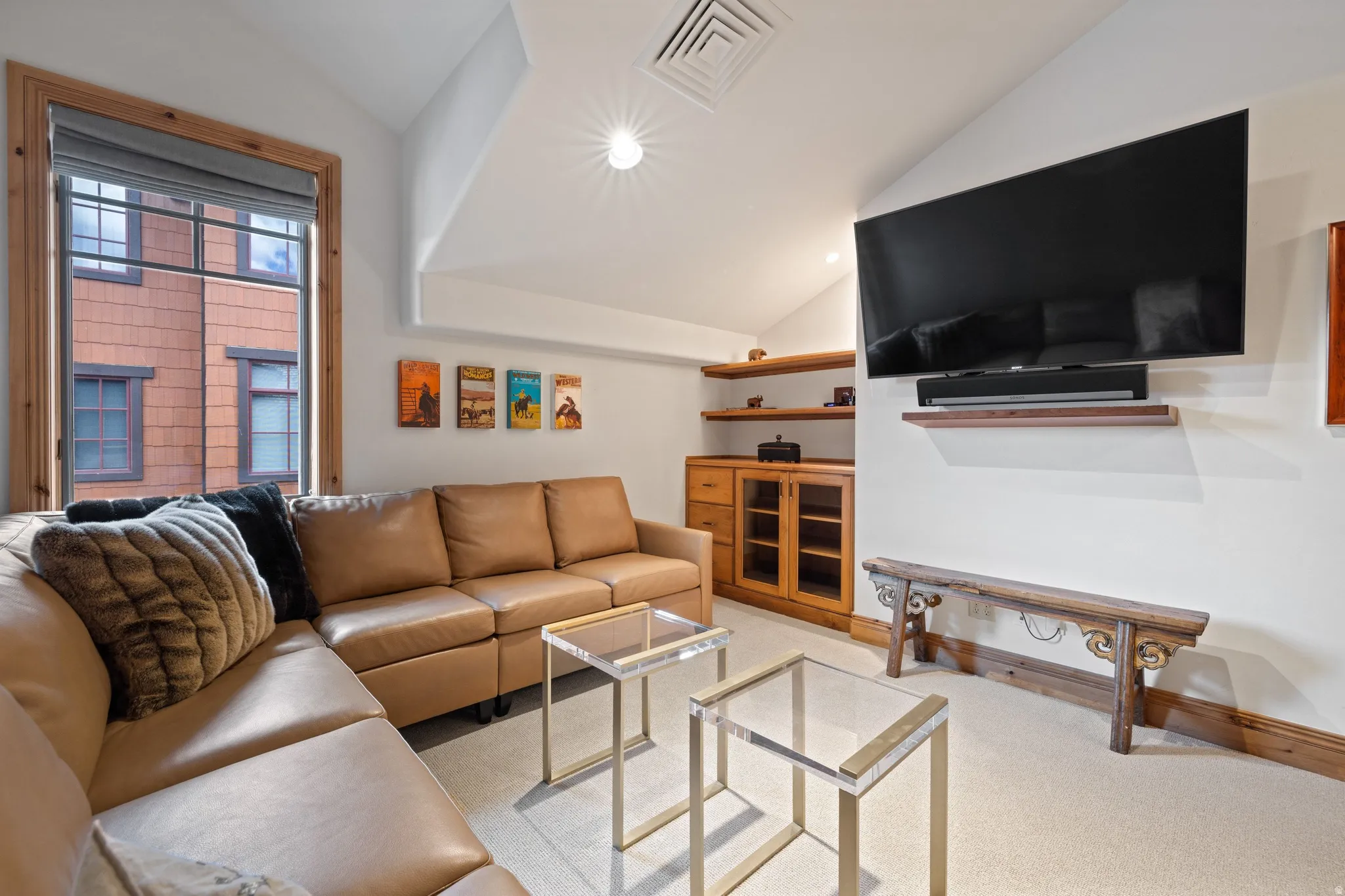 Recessed lighting illuminates the angled ceiling and light-colored carpeting